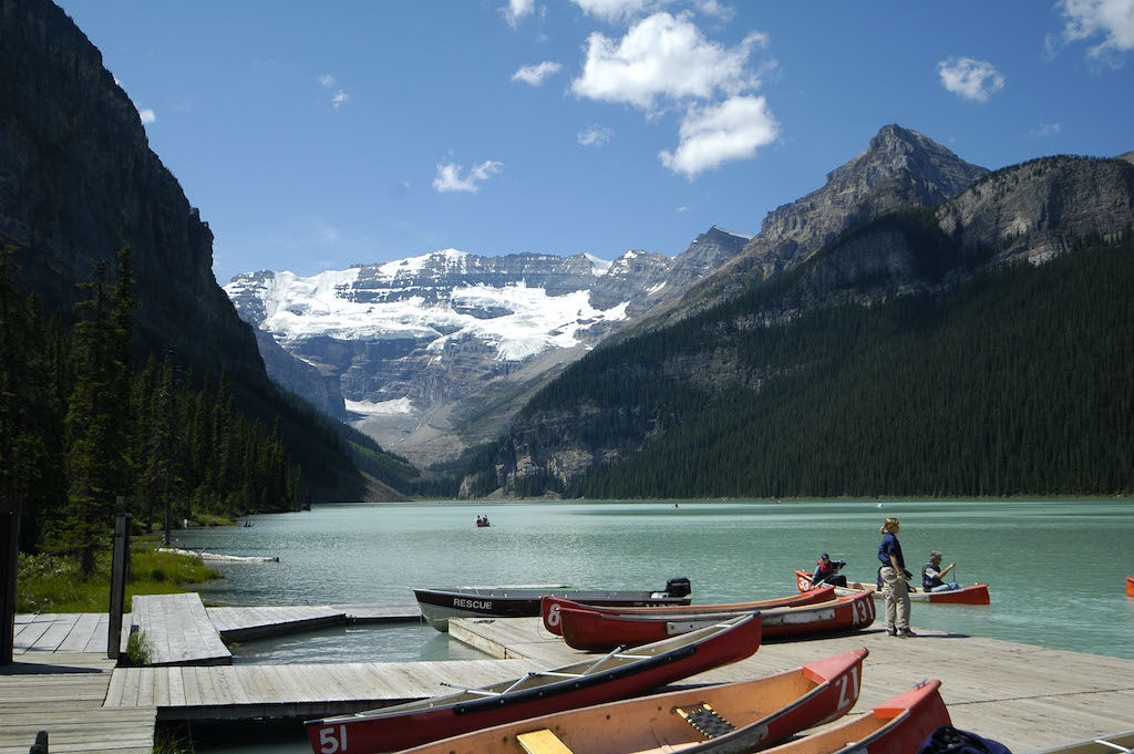image Glimpse the serene beauty of a glacial lake, where rowboats gently glide across turquoise waters against towering peaks