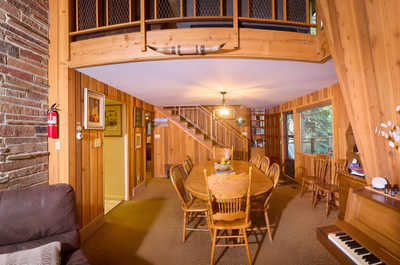 Spacious dining area with a wooden table, chairs, and warm wood-paneled walls.