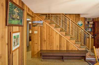 Wood-paneled entry with staircase, framed artwork on the wall, and a bench for gear or bags