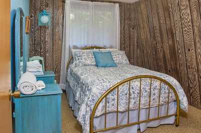 Light blue accents and patterned bedding complement a gold bed frame, mirror, and bedside table