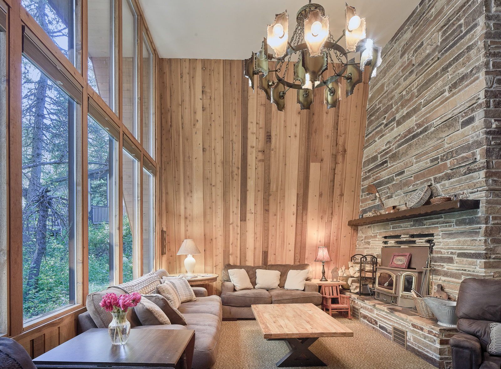 image Floor-to-ceiling windows frame forest views from the living area with stone fireplace and plush sofas
