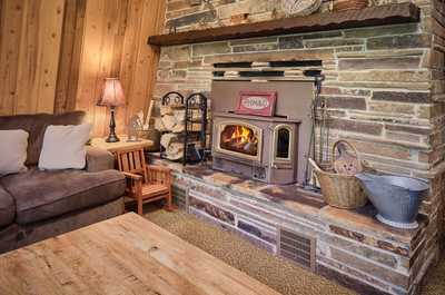 Stone fireplace glows in the living room, surrounded by wooden walls and a padded bench seat