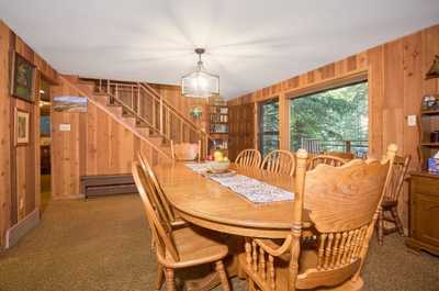 Wide dining room leads into the upper level, wood-paneled walls and natural light throughout