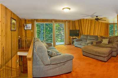 Wood-paneled walls, large windows, and two sofas fill the upper loft lounge area