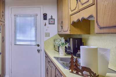 Oak cabinets and yellow countertop line the kitchen walls, with tile flooring and natural light