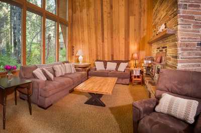 Sunlight fills the open living area with wooden walls, a central dining table, and a ceiling fixture