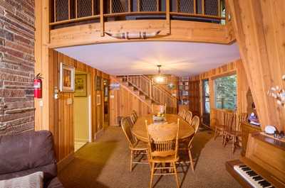 Spacious dining area with a wooden table, chairs, and warm wood-paneled walls