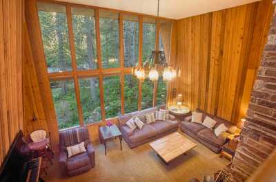 High ceilings and large windows overlook the trees, with plush seating and a chandelier below
