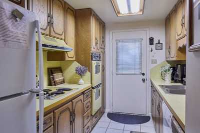 Oak cabinets, yellow countertop, and tile floor make up the main kitchen with door leading outside