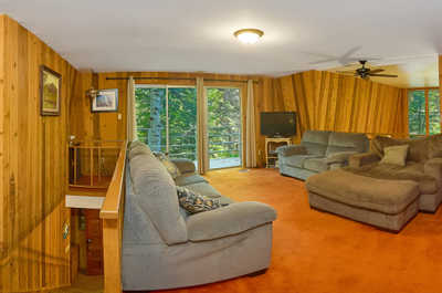 Wood-paneled walls, large windows, and two sofas fill the upper loft lounge area