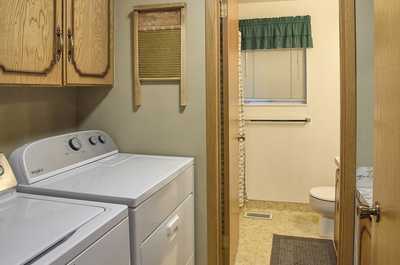 Washer and dryer along the wall above wooden cabinets, with a door leading to the bathroom
