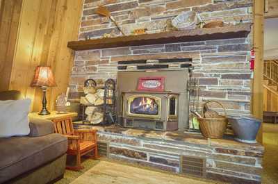 Brick fireplace with log insert sits in the corner, beside a small wooden chair and woven baskets