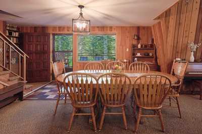 Dining table set with fruit bowl centerpiece, large windows overlooking the trees