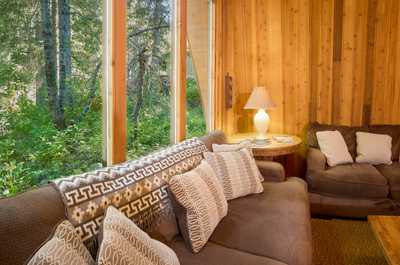 Two sofas face each other across a wooden coffee table, large windows bringing in natural light