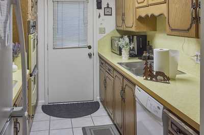 Narrow kitchen with vintage wood cabinets, exterior door, and a floral arrangement on the counter