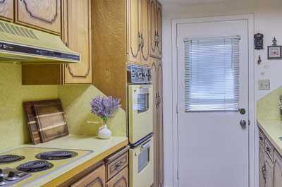 Kitchen with oak cabinets, yellow countertop, tile floor, and a woven rug near the back door