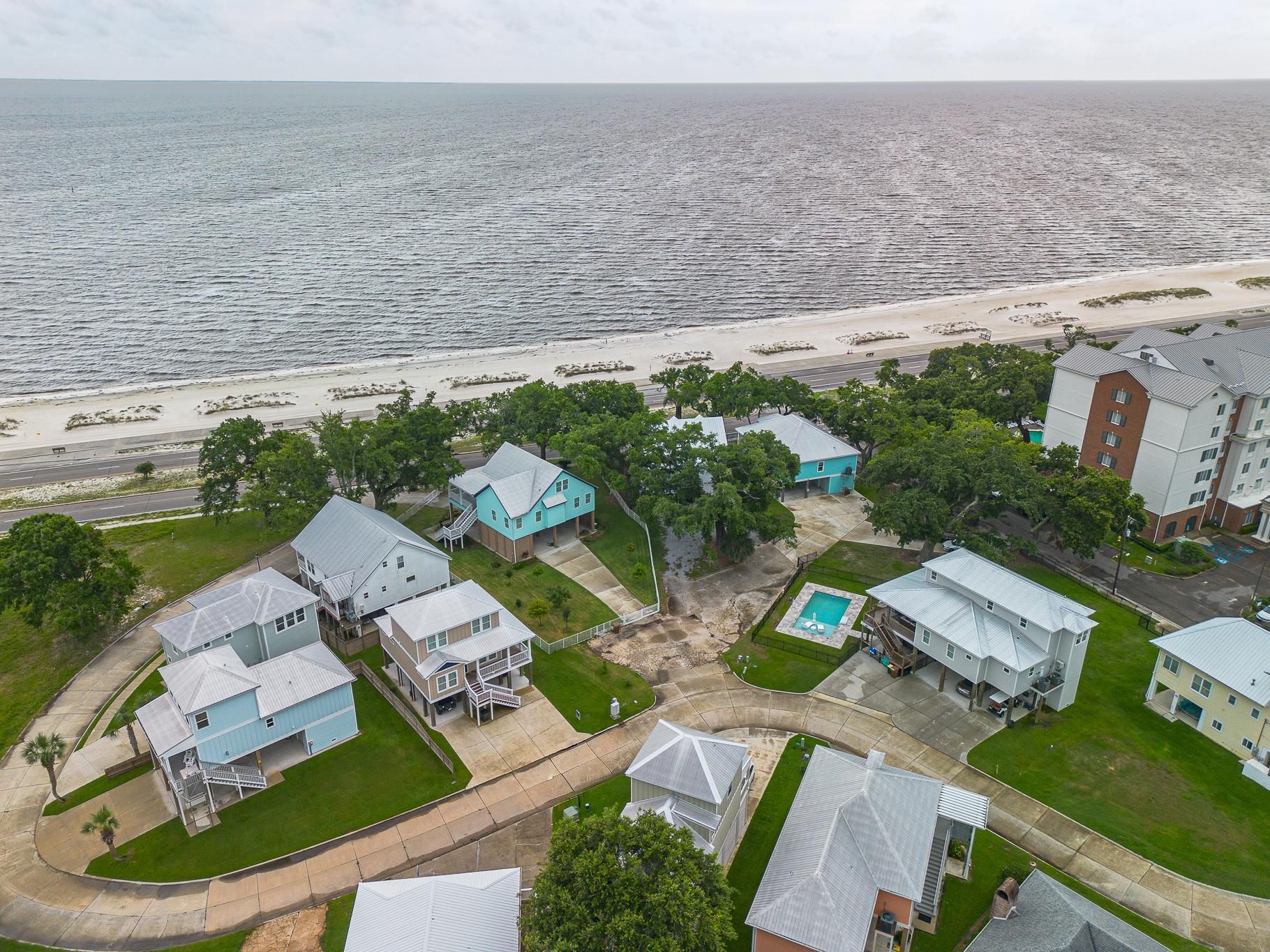 image Aerial view of the property set among green trees, surrounding homes, and the nearby Gulf of Mexico