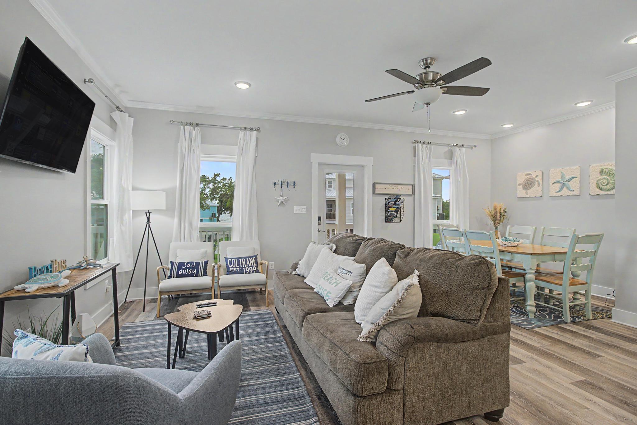 image Open-plan living area with luxury vinyl plank flooring, large windows, and a dining table with aqua chairs