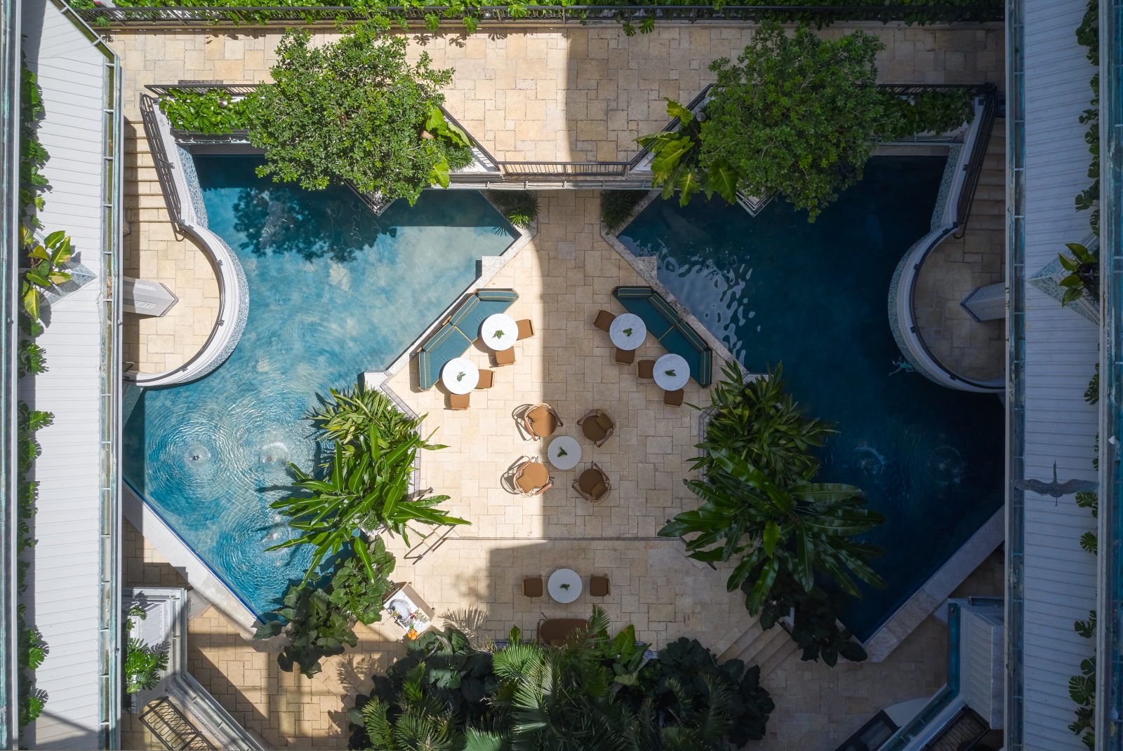 image Aerial view of the tranquil pools nestled within greenery, with lounge chairs and tables arranged poolside