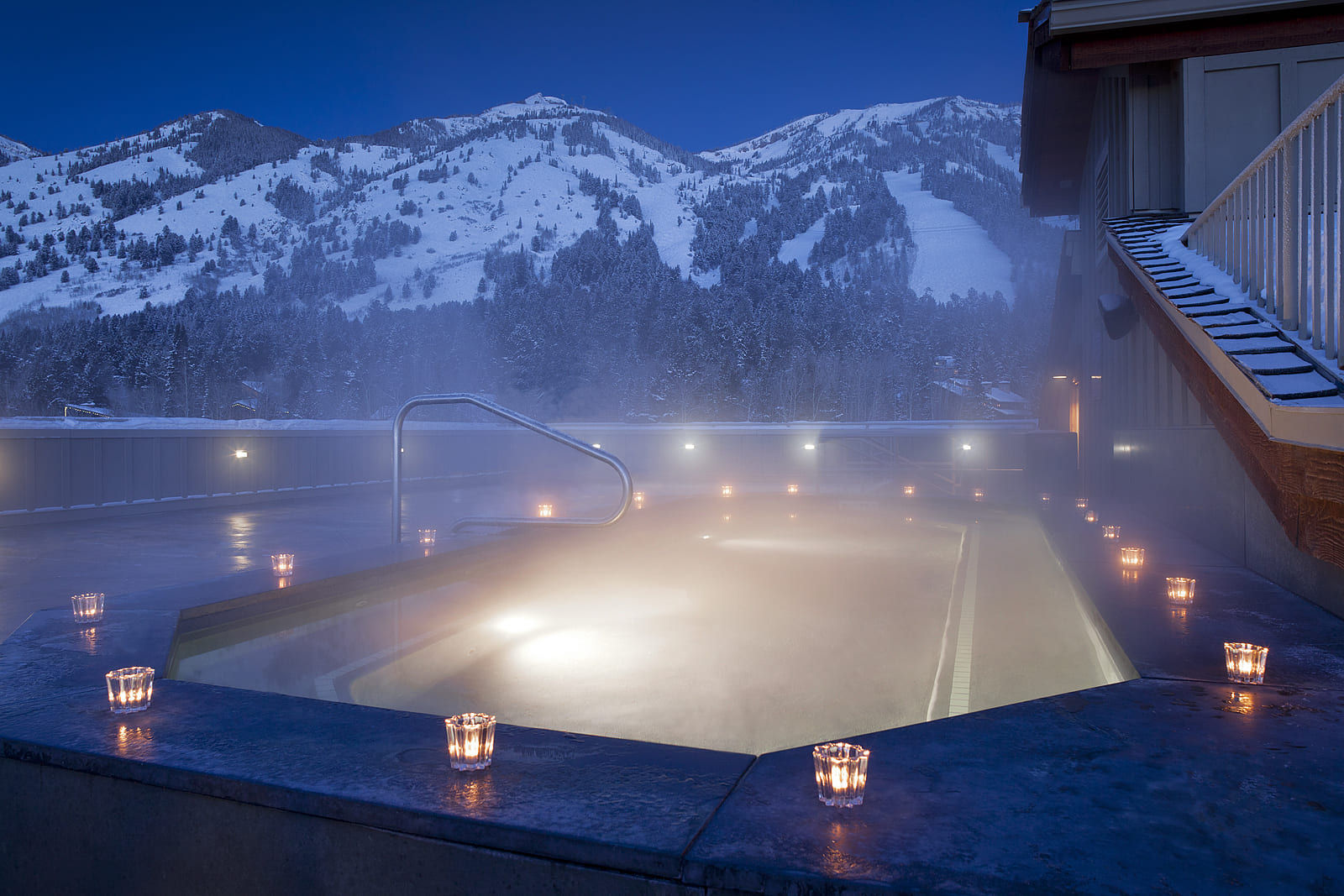 image Candles line the rooftop hot tub as dusk settles over the mountains.