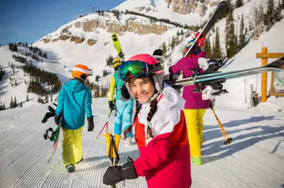 Boards and skis in hand, a group heads toward the slope.