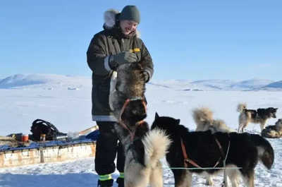 A musher greets the huskies before setting off on a snowy trail.