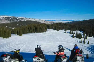 Four snowmobiles carve fresh tracks down the snowy mountainside near Jackson Hole.