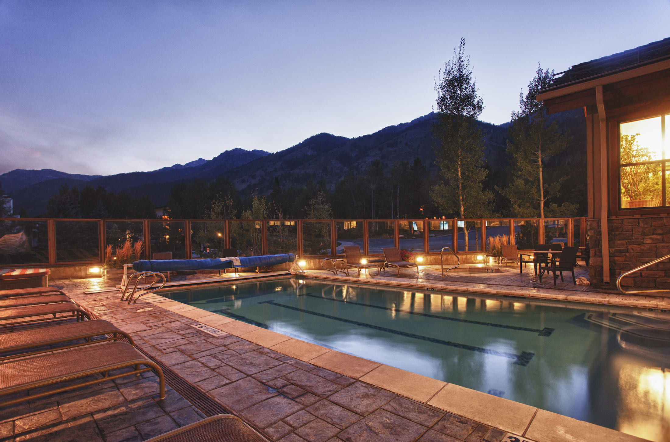 image Lounge chairs line the outdoor pool at Teton Mountain Lodge as evening falls.
