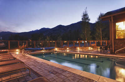 Lounge chairs line the outdoor pool at Teton Mountain Lodge as evening falls.