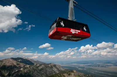 The aerial tram climbs above Jackson Hole through summer greenery.