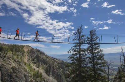 Hikers cross a rope bridge along a mountain trail near Jackson Hole.
