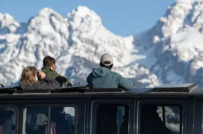 Guests on a winter safari watch for wildlife against the distant peaks.
