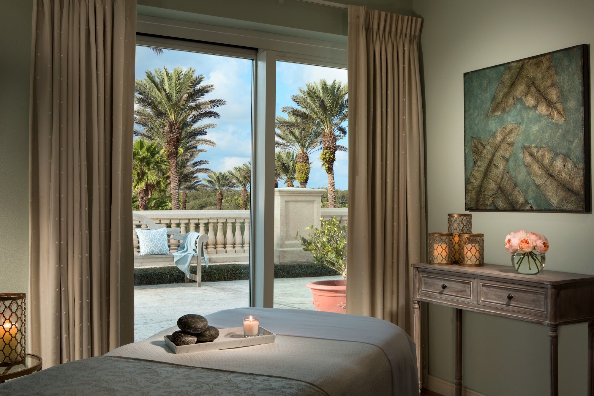 image Spa treatment room with a massage table, smooth stones, and a candlelit setting