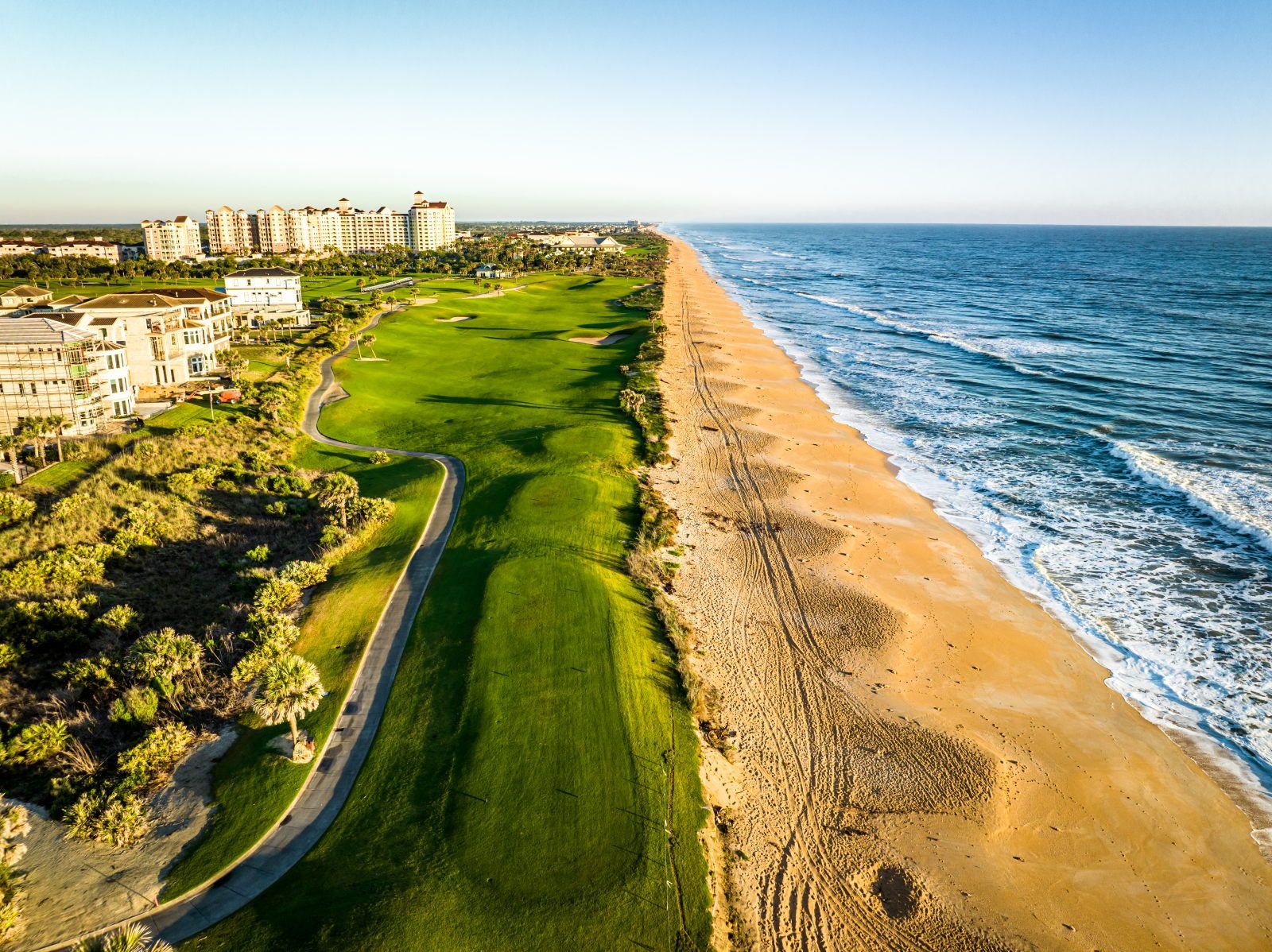 image Aerial view of a golf course bordering the Atlantic, with beachfront towers beyond