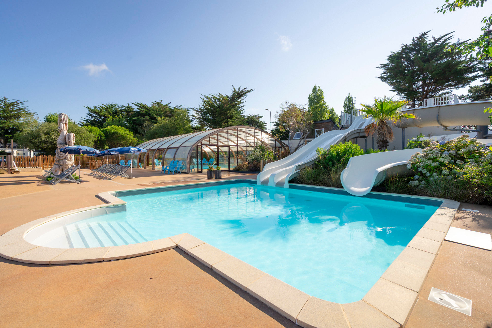 image The outdoor pool and water slides, next to the covered pool area.