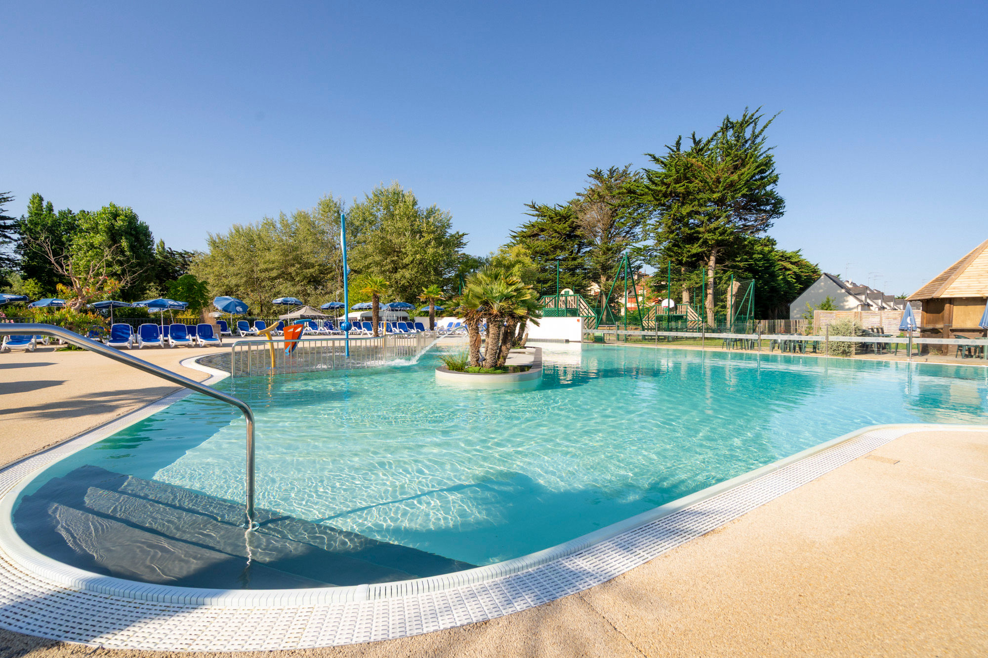 image The outdoor pool, lined with sun loungers beneath the trees.