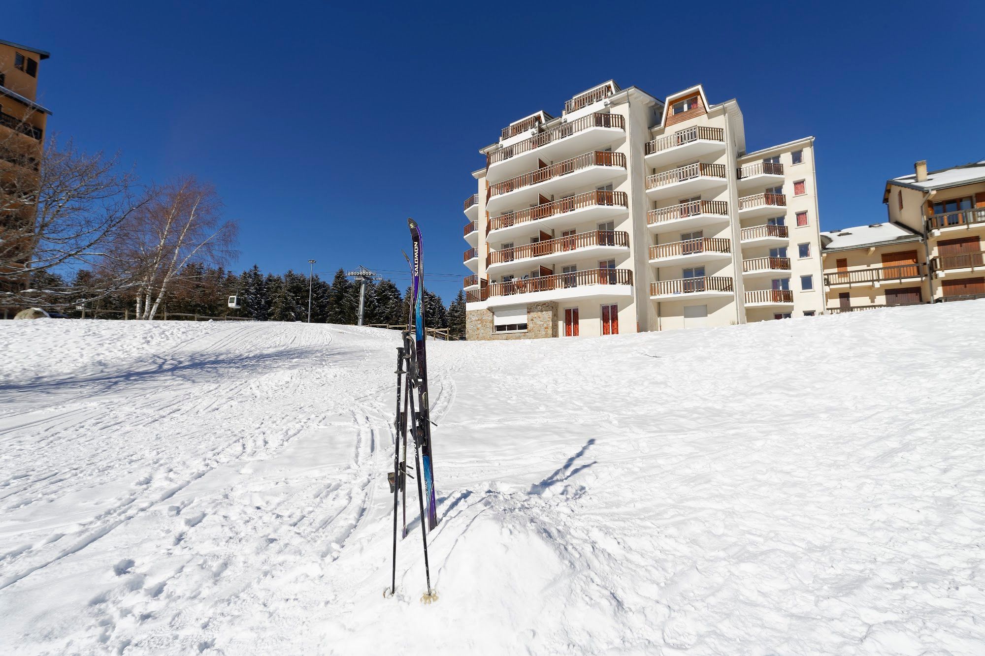 image Fresh ski tracks lead straight to the door under a clear sky.