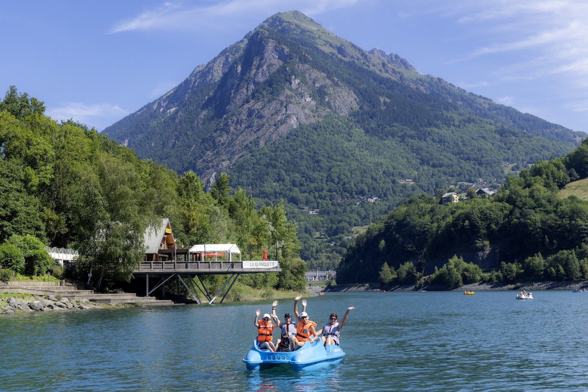 image Four people paddling a blue boat on a lake near mountains