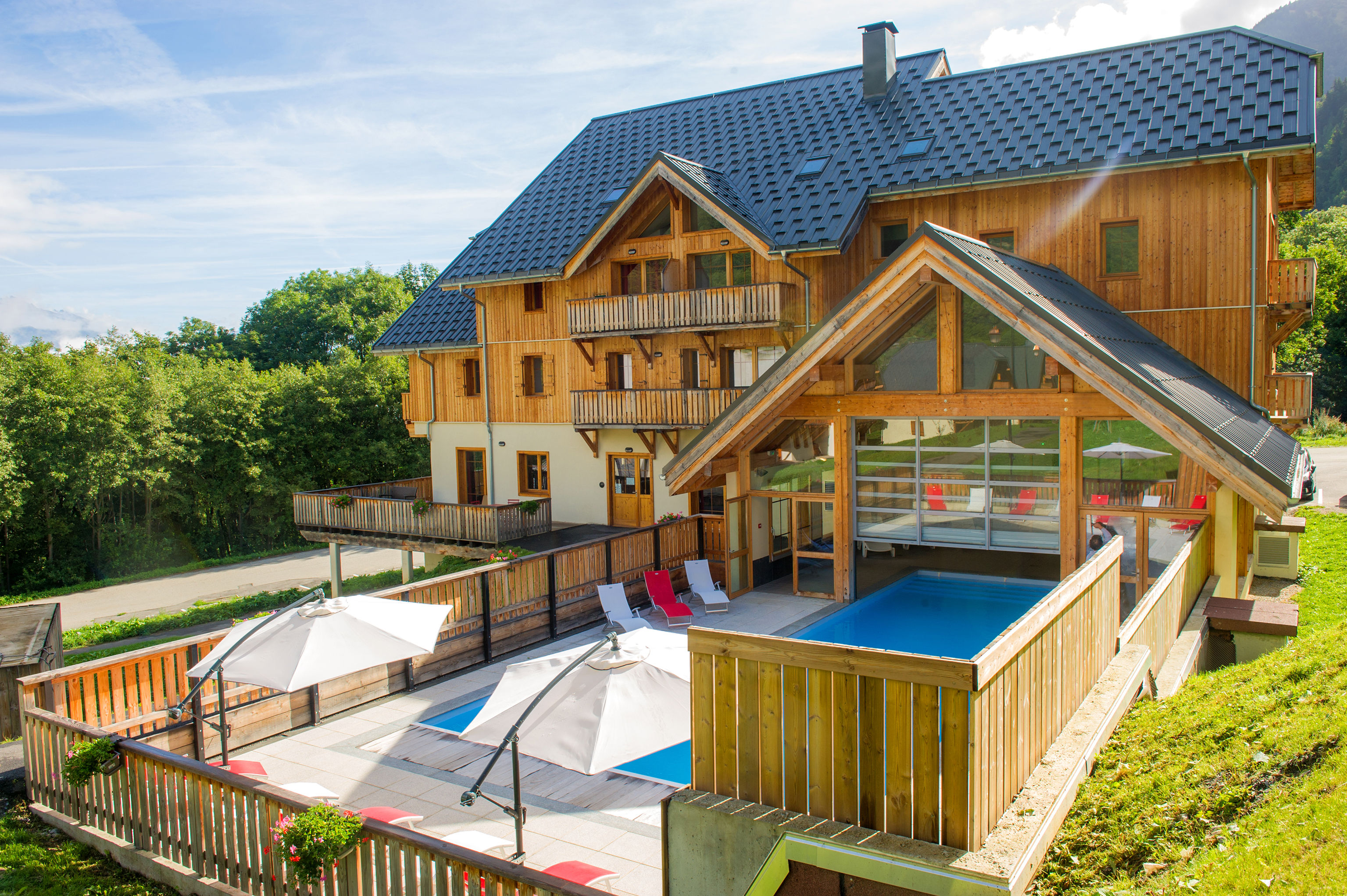 image Sun loungers line the seasonal pool against the wooden chalets.