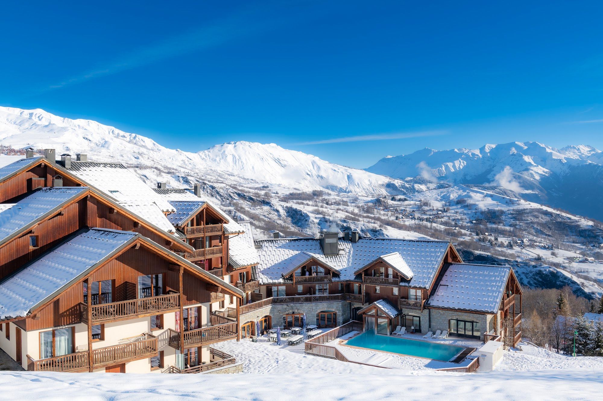 image Snowy landscape with multiple buildings and mountains.
