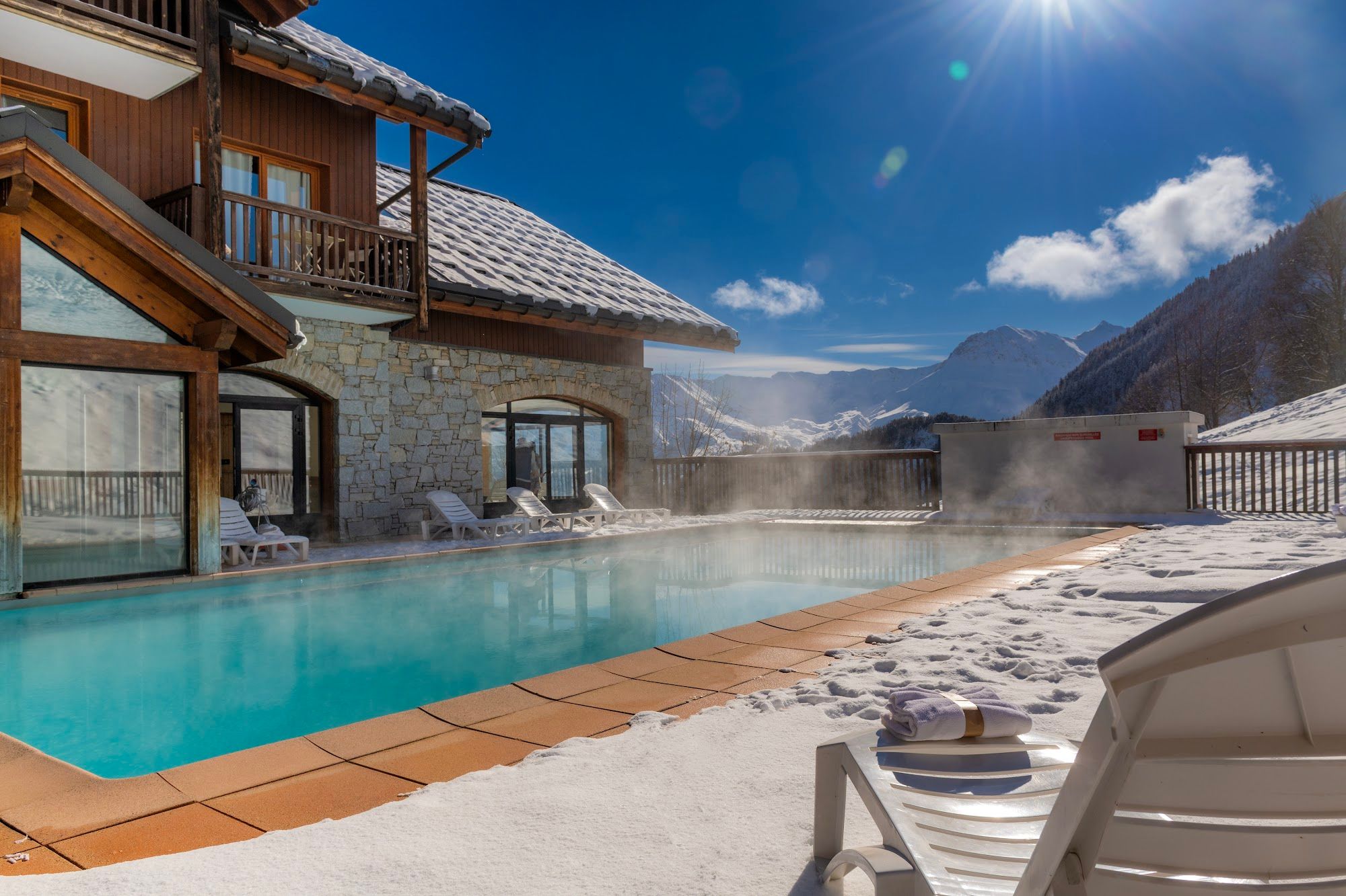 image Heated outdoor pool surrounded by snow and mountains.
