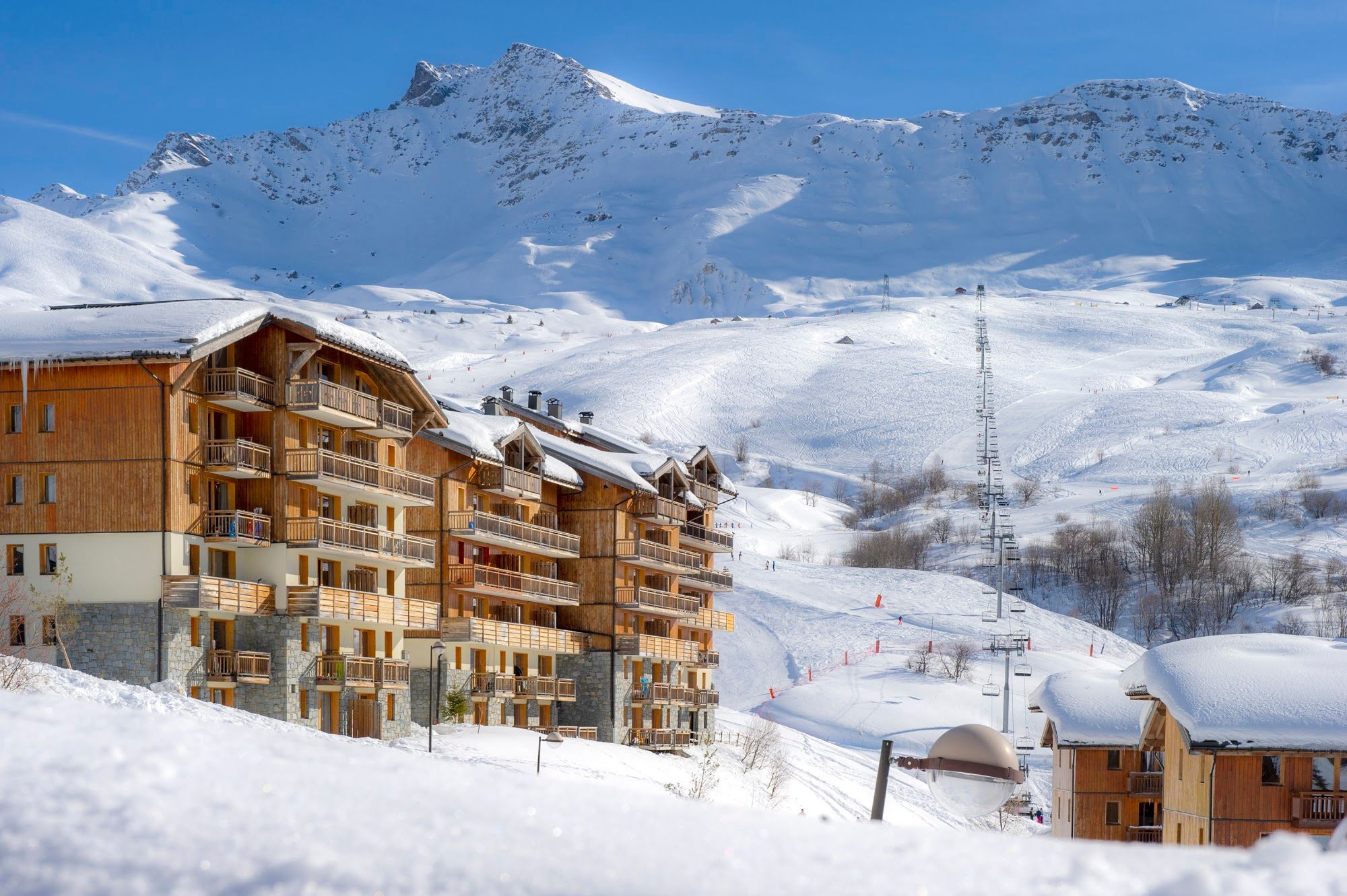image Wooden residence buildings beside a ski lift in a snowy landscape.