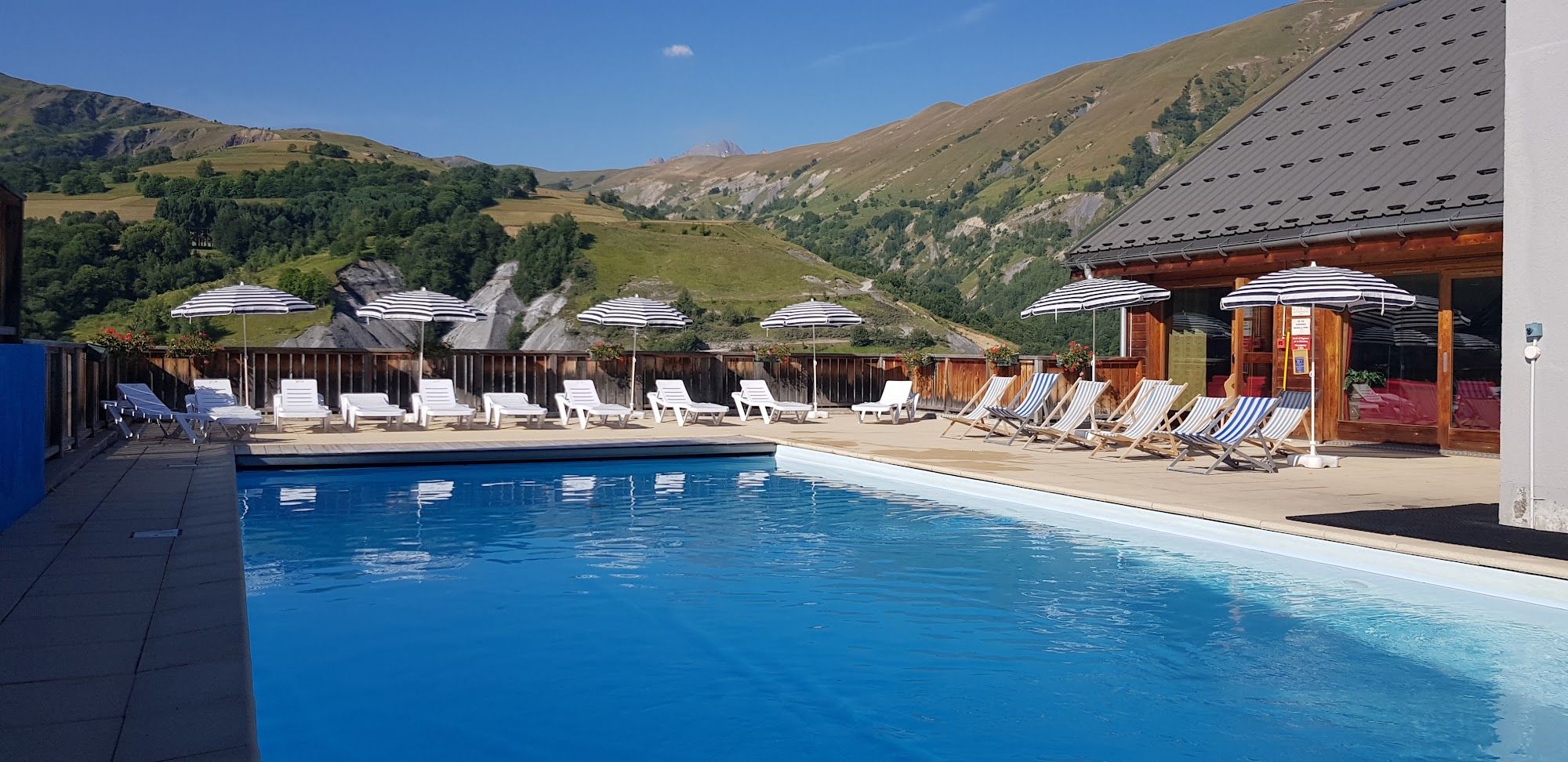 image Outdoor pool with umbrellas and deck chairs, mountain view, summer
