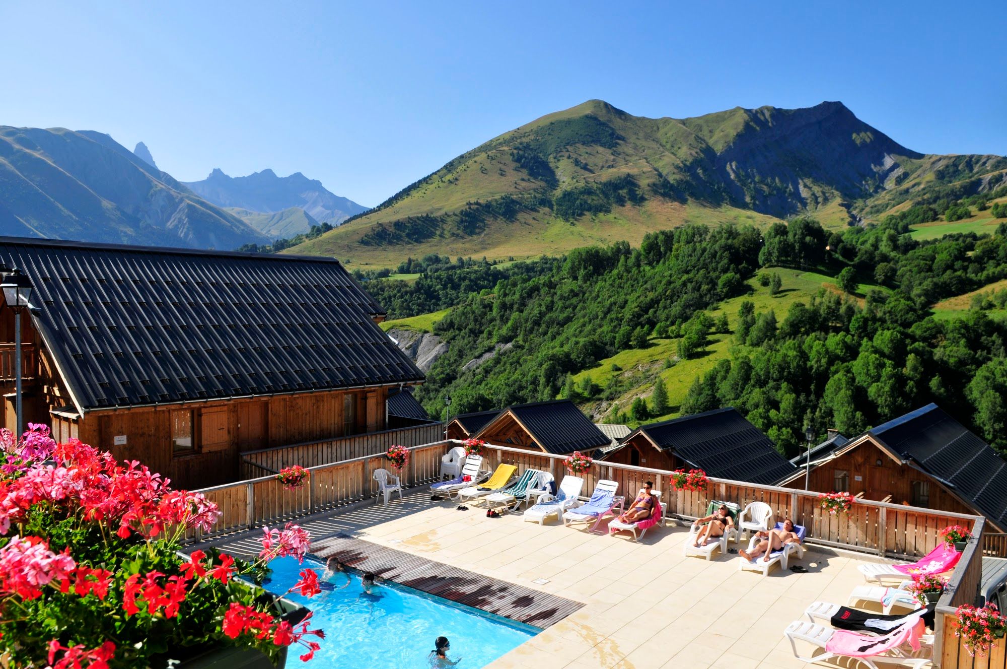 image Aerial pool + residence + guests sunbathing, flowers foreground, summer