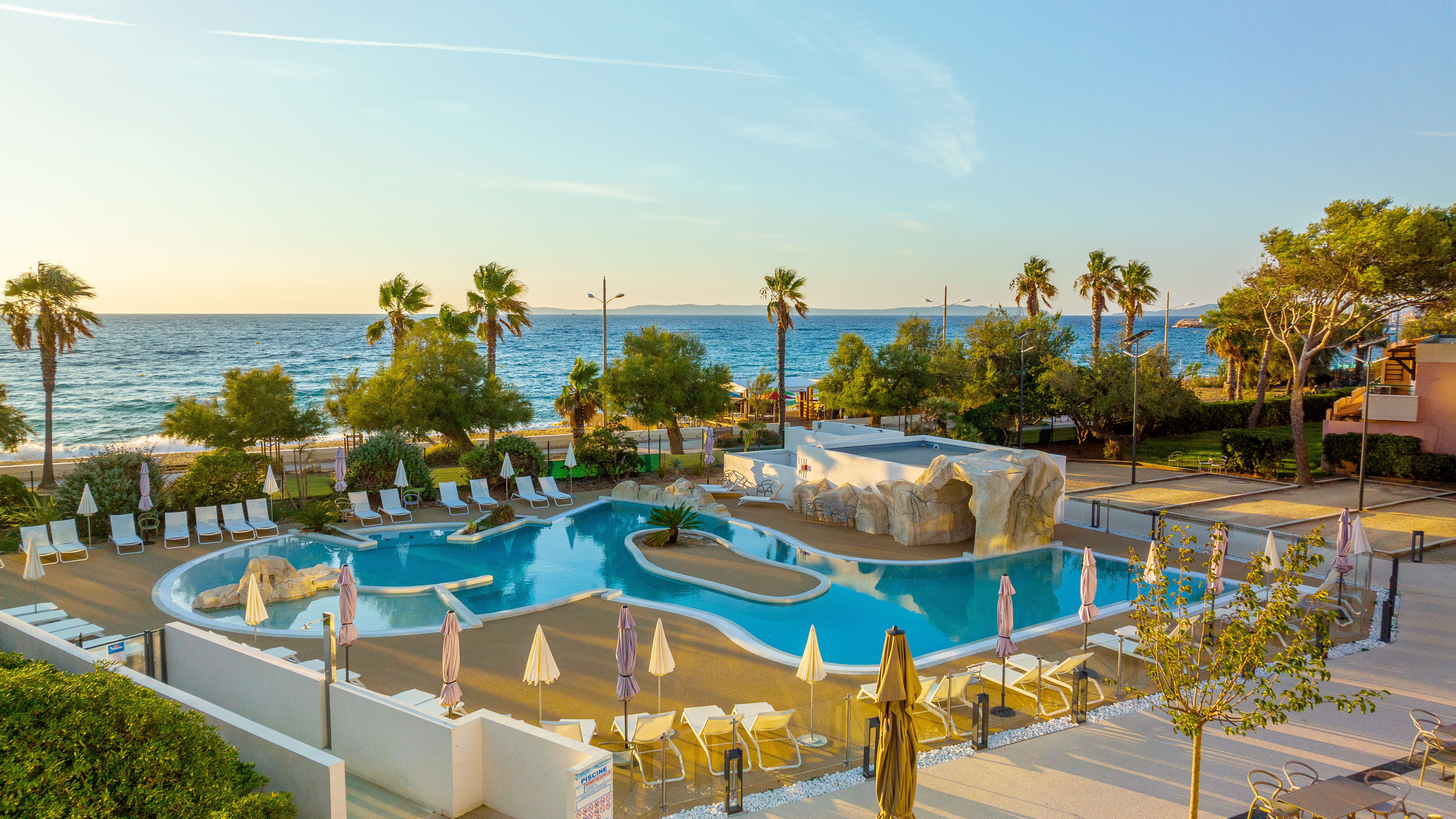 image Seasonal pool area with palm trees and sea views.