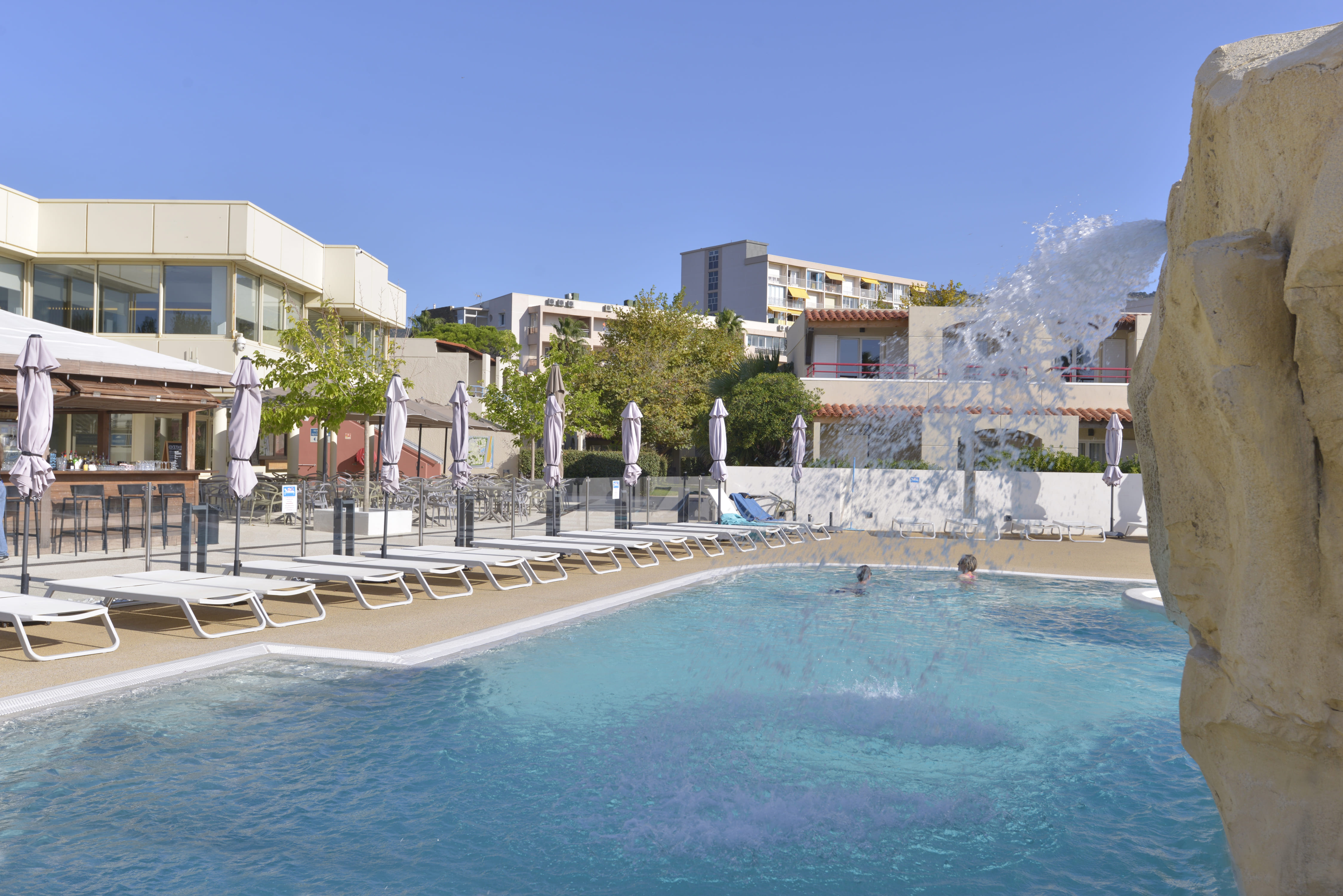 image Seasonal lagoon-style pool with a waterfall feature.