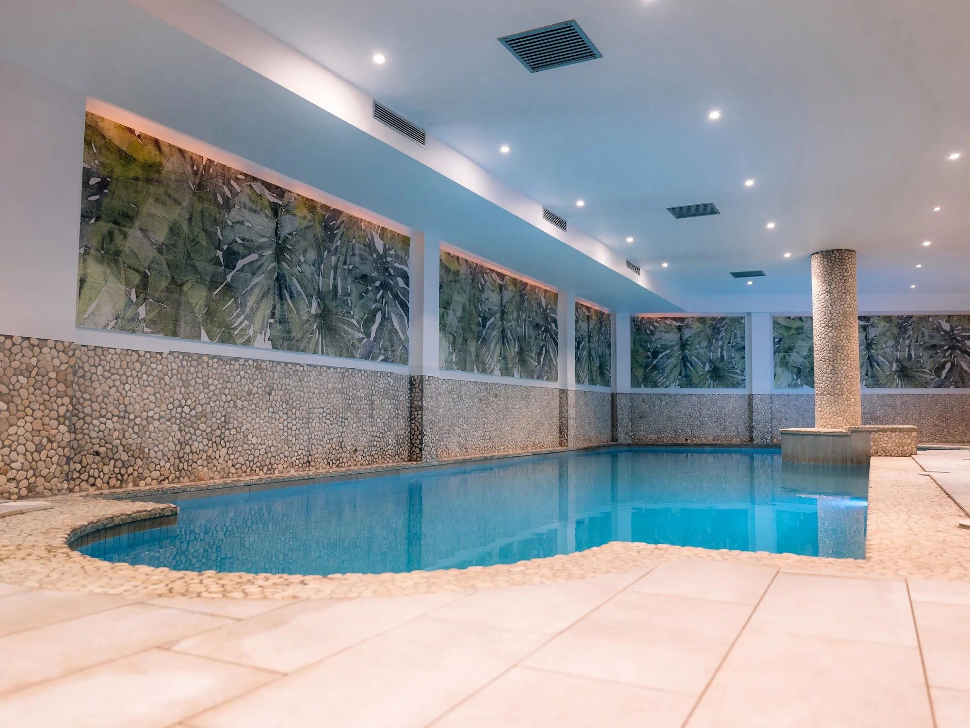 image Indoor pool with lounge chairs alongside.