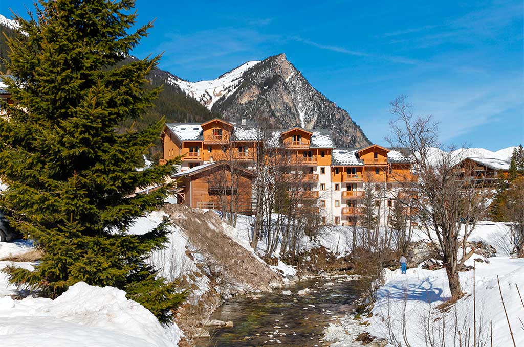 image Winter here, with snow banked along the stream and peaks rising behind.